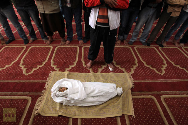 Palestinian mourners pray over the body of 18-month-old Eyad Abu Khosa, killed in the latest Israeli airstrikes, during his funeral in the Bureij refugee camp in central Gaza Strip.(AFP Photo / Mahmud Hams)